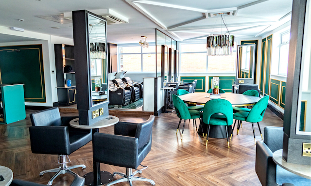 mirrored walls, black dining table and green chairs and hairdressing chairs in front of mirrors